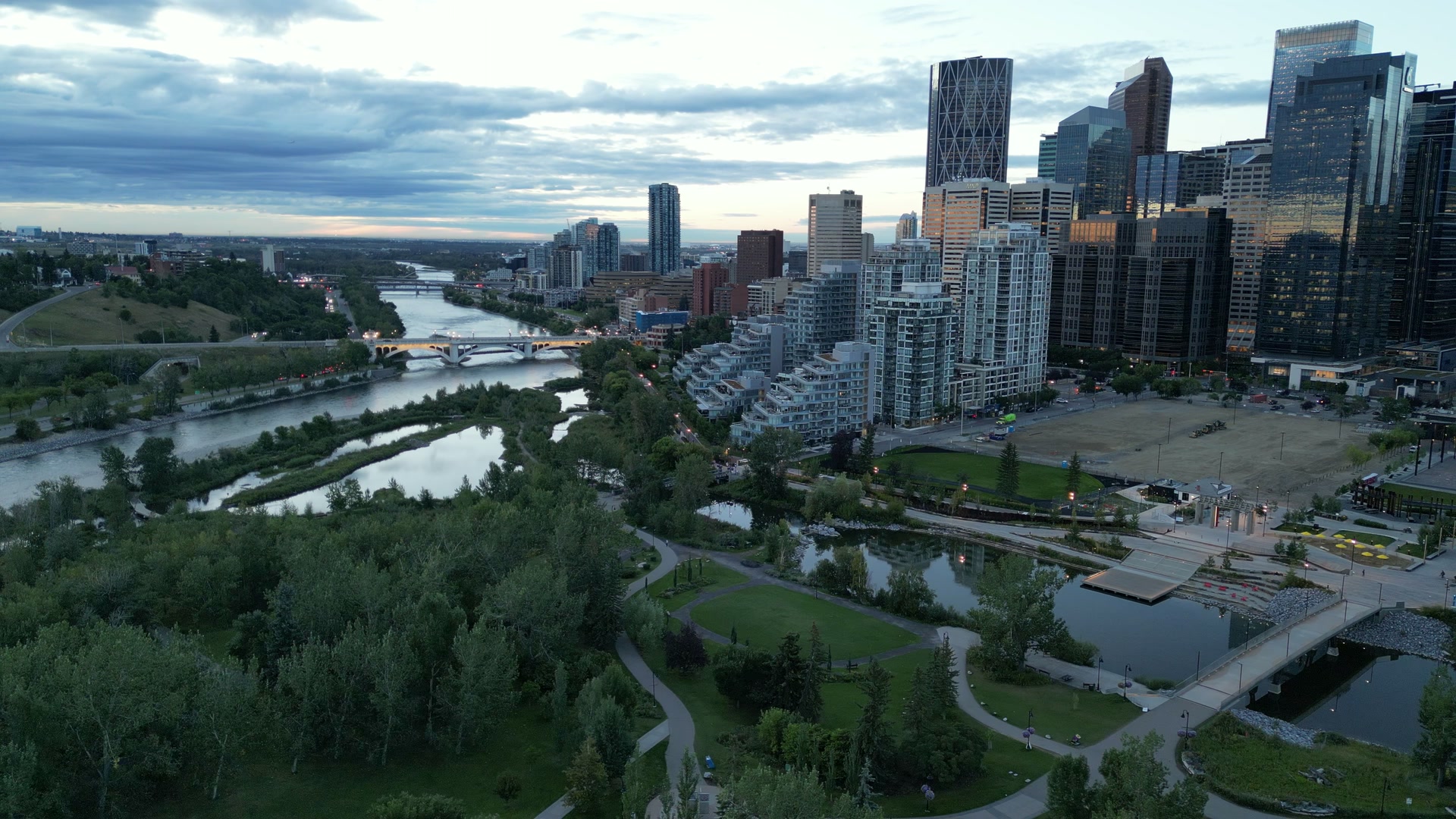Aerial film: Calgary from the Bow River at dusk, the downtown skyline, an ice cream shop in Cochrane from directly above, a café’s espresso bar from above, a private estate in the foothills, a timber wedding hall, and dusk over a valley from a forested ridge.